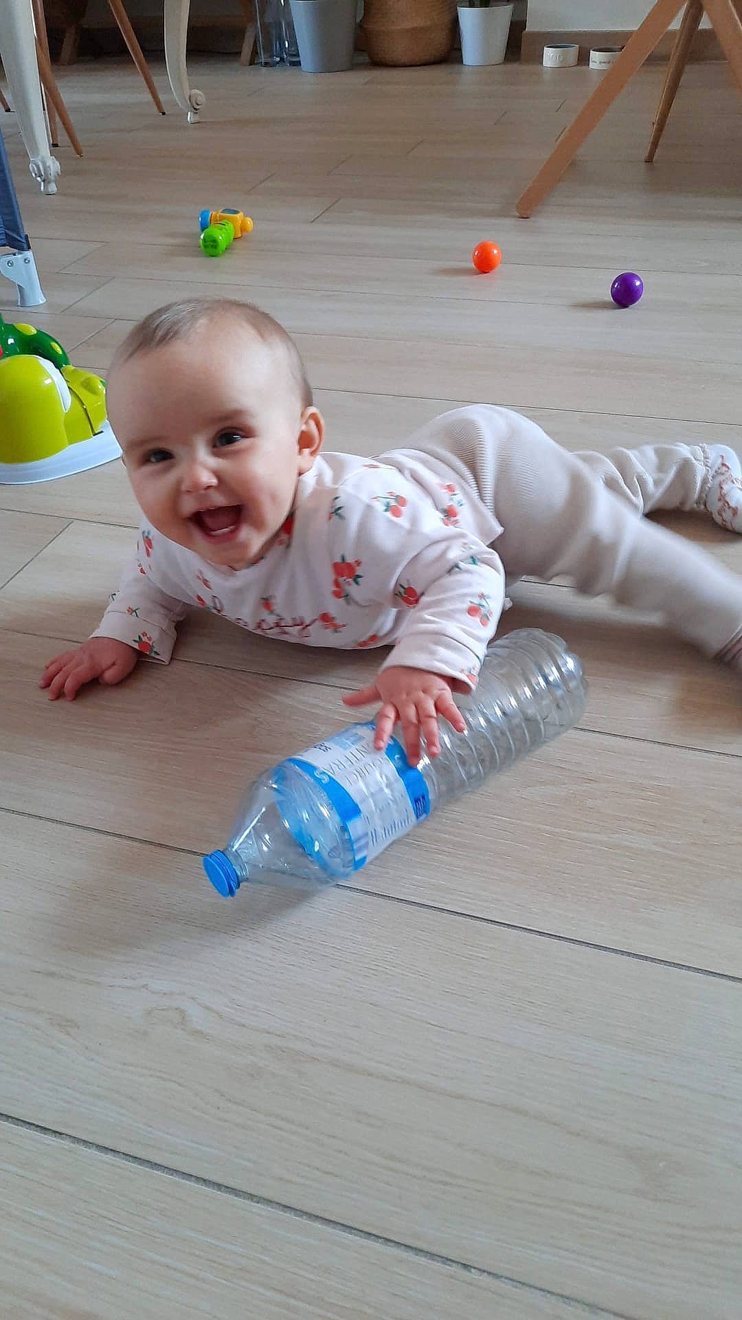 Miya a rejoint le concours — aidez-le/la à gagner de superbes lots ! baby, baby_toddler_clothing, balloon, bottle, cheek, child, crawling, floor, flooring, foot, happy, hardwood, joy, leisure, person, plastic_bottle, sitting, skin, smile, toddler