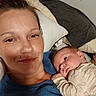 adult, baby, bed, bedroom, blanket, blue_shirt, cozy, eyes, face, family, indoors, infant, lying_down, mother, newborn, pajamas, pillows, portrait, relaxed, selfie