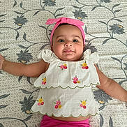Reyna joined the competition — help win amazing prizes! baby, infant, child, smiling, headband, pink_clothing, white_top, embroidery, lying_down, bedspread, floral_pattern, cute, portrait, indoors, person, happy, young_child, skin, face, arm