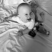Sacha a rejoint le concours — aidez-le/la à gagner de superbes lots ! baby, smiling, bed, blanket, stuffed_toy, clothing, happy, infant, face, person, indoors, cute, child, lying_down, soft, monochrome, toddler, playful, comfort, toy