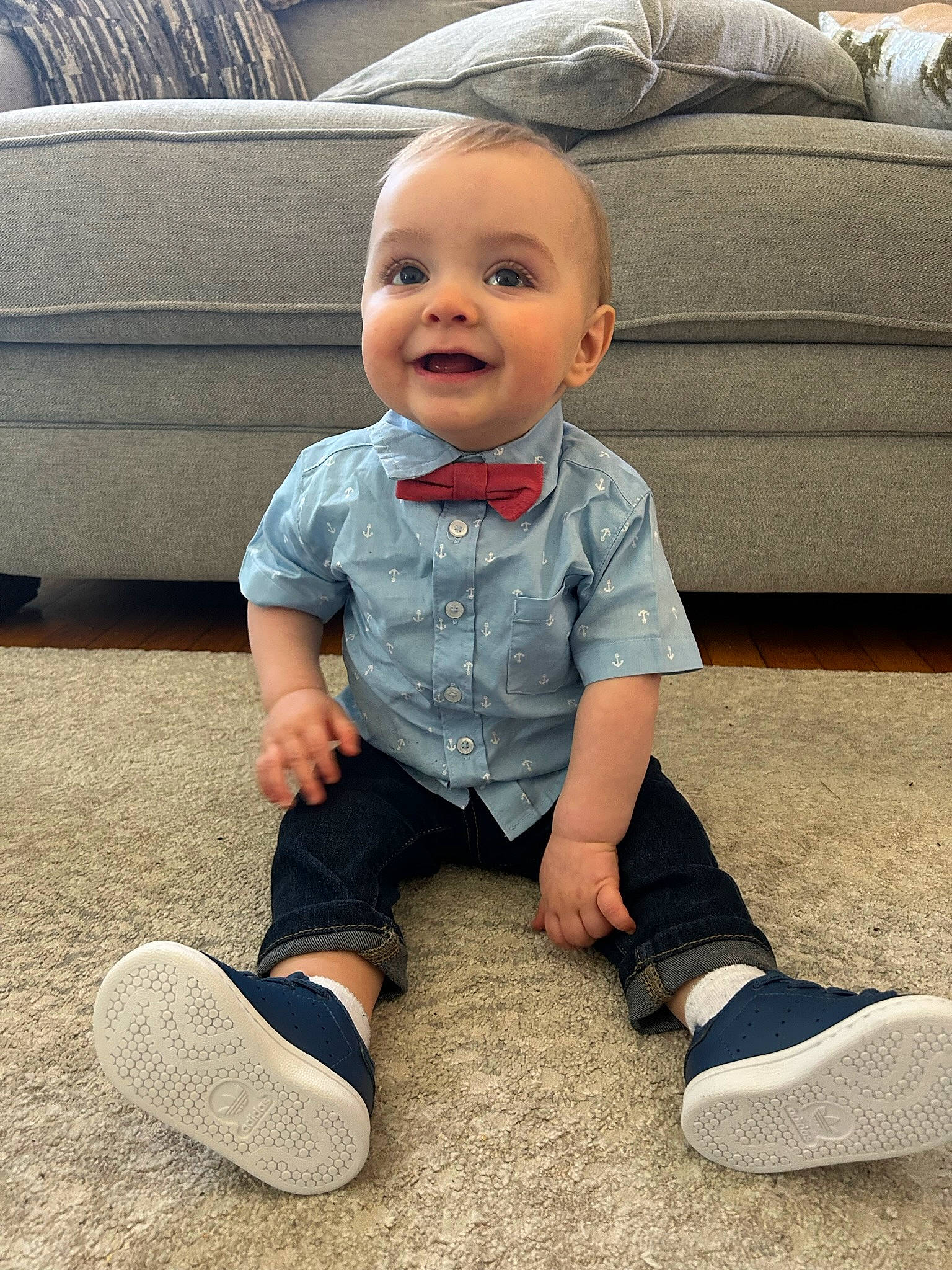 Logan is registered to the contest to win money with this photo: baby, baby_toddler_clothing, black, child, comfort, couch, eye, floor, flooring, footwear, happy, head, joy, person, shoe, sleeve, smile, sneakers, standing, toddler