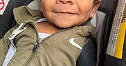 Adonis joined the competition — help win amazing prizes! baby, child, smiling, face, curly_hair, car_seat, jacket, zipper, clothing, portrait, closeup, seatbelt, infant, cute, happy, young, person, indoor, casual, expression