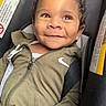 baby, child, smiling, face, curly_hair, car_seat, jacket, zipper, clothing, portrait, closeup, seatbelt, infant, cute, happy, young, person, indoor, casual, expression