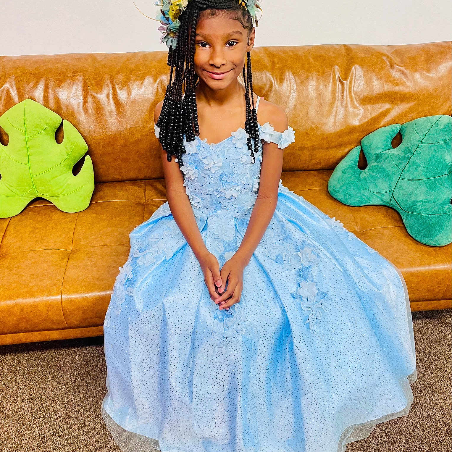 Quiari is registered to the contest to win money with this photo: child, girl, dress, blue_dress, princess, flower_crown, braided_hair, smile, couch, leather_couch, pillow, leaf_pillow, indoor, carpet, portrait, seated, happy, young, decor, fashion