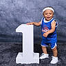 toddler, child, smiling, blue_shorts, blue_shirt, white_sneakers, headband, number_one, standing, studio_background, carpet, portrait, happy, cute, indoor, person, baby, sporty, photography, pose