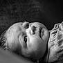 baby, infant, newborn, face, eye, cheek, portrait, black_and_white, monochrome, close_up, gaze, lying_down, clothing, fabric, soft_texture, hair, eyelashes, head, skin, sleepy