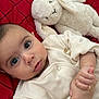 baby, infant, stuffed_animal, plush_toy, bunny, red_blanket, clothing, hands, face, eyes, portrait, cute, soft_toy, lying_down, child, indoors, closeup, expression, person, resting
