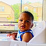 Damir is registered to the contest to win money with this photo: baby, high_chair, indoor, window, house, child, curious, table, furniture, daylight, portrait, face, skin, clothing, sleeveless_shirt, earring, hands, expression, home, background