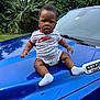 baby, child, blue, car_hood, truck, nike, striped_clothing, socks, bracelet, earrings, outdoor, banana_plants, greenery, nature, vehicle, portrait, curious, sitting, daylight, expression