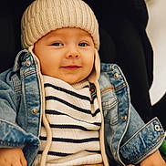 Nélyo a rejoint le concours — aidez-le/la à gagner de superbes lots ! baby, child, hat, knit_hat, denim_jacket, striped_sweater, brown_pants, smile, face, portrait, sitting, cute, cozy, warm_lighting, indoor, clothing, baby_hand, casual, fashion, infant