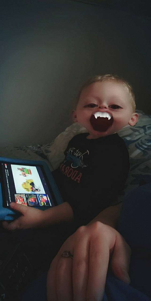 Jayden is registered to the contest to win money with this photo: baby, baby_toddler_clothing, cheek, child, display_device, ear, finger, gadget, games, humour, iris, laugh, lip, multimedia, nail, organ, person, skin, tablet_computer, tongue