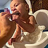 baby, child, high_chair, hand, food, chocolate, eating, tissue, indoor, person, face, mouth, skin, furniture, tableware, home, head, arm, human, expression