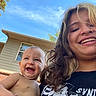 Apollo is registered to the contest to win money with this photo: baby, child, smiling, happy, outdoor, sky, house, window, person, hair, face, holding, shirt, braces, sunlight, blue_sky, tree, hand, portrait, candid