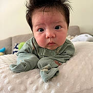 Grace joined the competition — help win amazing prizes! baby, infant, face, hair, spiky_hair, pajamas, green_clothing, pillow, texture, indoor, cute, child, resting, curious, portrait, soft_light, expression, young, person, closeup