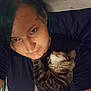 affection, animal, black_shirt, blue_hair, cat, closeup, comfort, cuddle, face, friendship, hair, home, indoor, lying_down, person, pet, relaxation, sleepy_cat, tabby_cat, tattoo