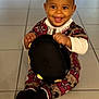 baby, child, smiling, sitting, hat, black_hat, floor, tile_floor, indoors, clothing, patterned_clothing, happy, portrait, person, cute, bright, young_child, holding_object, baby_socks, head