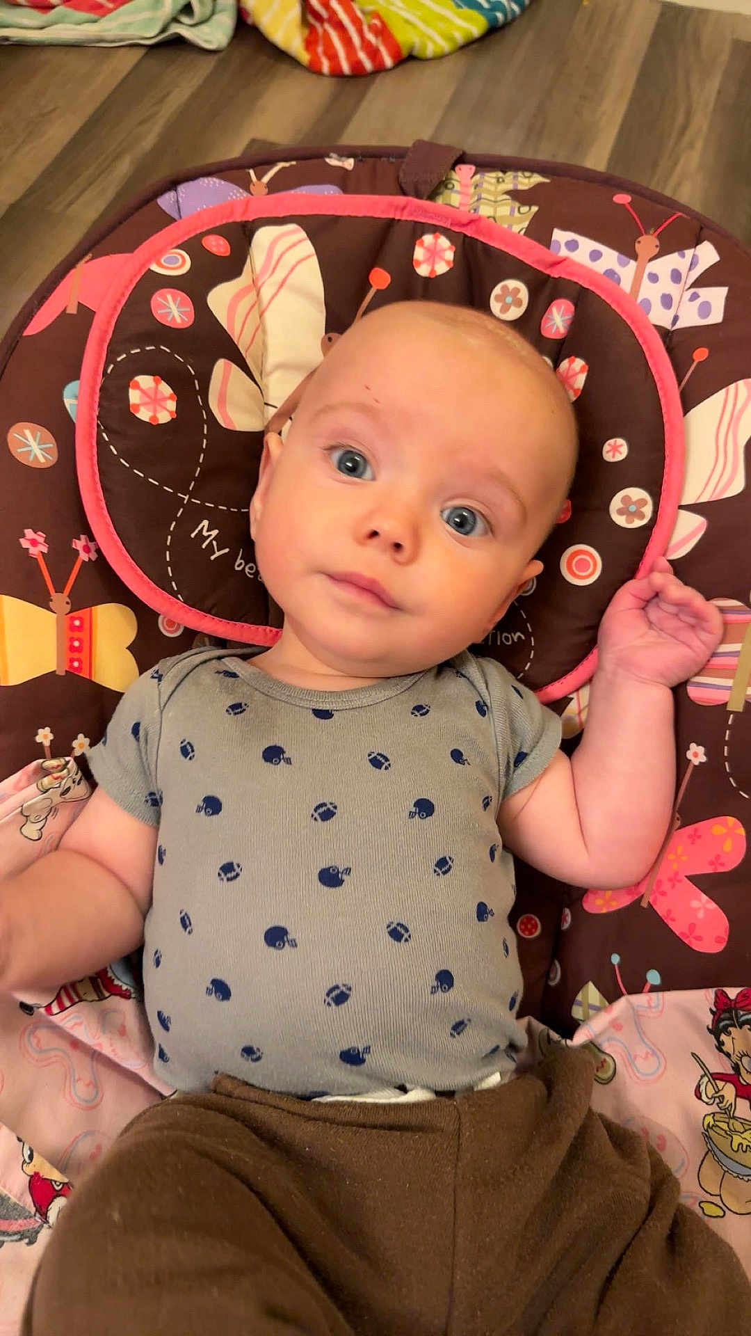Atlas joined the competition — help win amazing prizes! baby, infant, child, blue_eyes, onesie, brown_pants, pillow, butterfly_pattern, floor, wood_floor, cute, lying_down, indoors, clothing, person, young_child, face, head, hand, expression