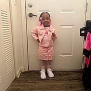 Autumn is registered to the contest to win money with this photo: child, girl, pink_clothing, denim_jacket, skirt, white_sneakers, striped_socks, standing, posing, hair_beads, flower_beads, indoors, door, floor, wall, bracelet, smiling, confident, home, fashion