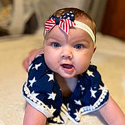Riverlynn is registered to the contest to win money with this photo: arm, baby, blue_clothing, bow, child, closeup, crawling, curious, cute, eyes, face, happy, headband, indoor, infant, mouth, portrait, skin, soft_surface, stars