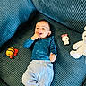 Maher is registered to the contest to win money with this photo: baby, child, infant, smiling, happy, sitting, lying_down, portrait, face, blue_clothing, white_pants, couch, corduroy, stuffed_animal, bunny_toy, bee_toy, indoor, playtime, colorful, family_photo