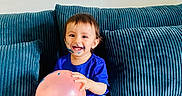 Maher joined the competition — help win amazing prizes! child, toddler, baby, smiling, face_paint, balloon, sofa, couch, sitting, indoors, portrait, happy, blue_clothing, white_shorts, barefoot, brown_hair, face, furniture, playful, photography