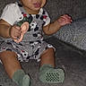 baby, child, sitting, sofa, couch, toy, spoon, smiling, portrait, indoors, clothing, overalls, socks, green_socks, flash_photography, home, furniture, infant, playful, patterned_clothing