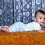 Adriel is registered to the contest to win money with this photo: baby, infant, child, lying_down, curtains, polka_dot, orange_fur, white_shoes, blue_clothing, bracelet, indoor, portrait, cute, young_child, face, smiling, socks, shorts, shirt, studio_photo