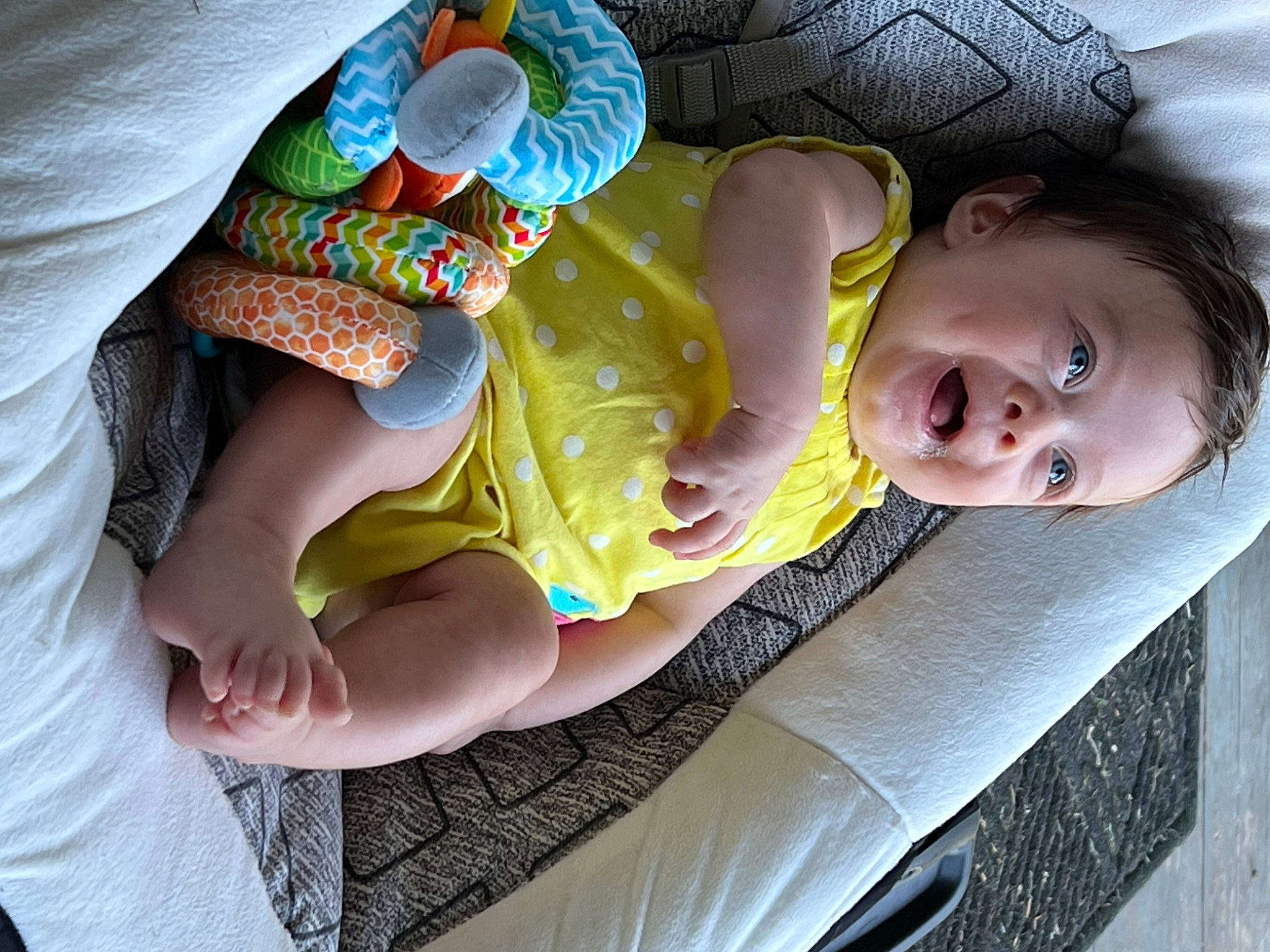 Scarlett is registered to the contest to win money with this photo: baby, baby_products, baby_toddler_clothing, cheek, child, comfort, finger, foot, fun, gesture, hand, happy, human_leg, leg, nail, person, sitting, skin, smile, thumb