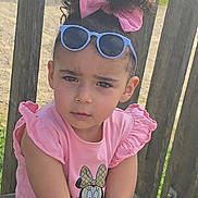 Alyah a rejoint le concours — aidez-le/la à gagner de superbes lots ! child, girl, pink_clothing, sunglasses, hair_bow, curly_hair, bench, wooden_fence, outdoor, sunlight, serious_expression, casual_wear, person, portrait, summer, young_child, fashion, cute, daylight, nature