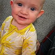 Vidalia is registered to the contest to win money with this photo: baby, blanket, child, closeup, clothing, cozy, cute, face, happy, indoor, infant, onesie, person, portrait, sitting, smile, soft_texture, sun_pattern, yellow, young_child