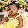 baby, child, toddler, yellow_dress, curly_hair, hair_bows, earrings, chair, indoor, portrait, flower_basket, background, colorful, cute, studio_photography, smiling, skin, person, fashion, decor