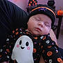 Aria joined the competition — help win amazing prizes! baby, sleeping, halloween, costume, ghost, pumpkin, skull, beanie, spider, string_lights, decorations, indoor, cute, infant, child, holiday, festive, person, black_clothing, soft_lighting