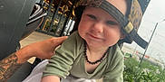 Oscar-Dayne is registered to the contest to win money with this photo: toddler, child, cap, leopard_print, necklace, tattoo, hand, outdoor, cafe, greenery, string_lights, smile, face, person, clothing, modern, building, window, daylight, casual