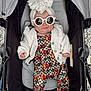 baby, stroller, sunglasses, headwrap, bow, white_cardigan, patterned_outfit, cherry_pattern, designer_logos, infant, child, fashion, cute, smiling, outdoor, footwear, clothing, seat, baby_accessory, person