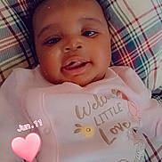 Ky'Manii is registered to the contest to win money with this photo: baby, infant, child, portrait, smiling, tongue_out, lying_down, pink_outfit, onesie, plaid_blanket, cushion, indoor, close_up, face, curly_hair, happy, heart_sticker, date_overlay, cartoon_print, photography