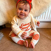 Lily joined the competition — help win amazing prizes! baby, child, smile, headband, orange, pumpkin, carpet, sitting, hand, clothing, cute, indoor, radiator, white_cardigan, feet, portrait, happy, face, infant, cozy