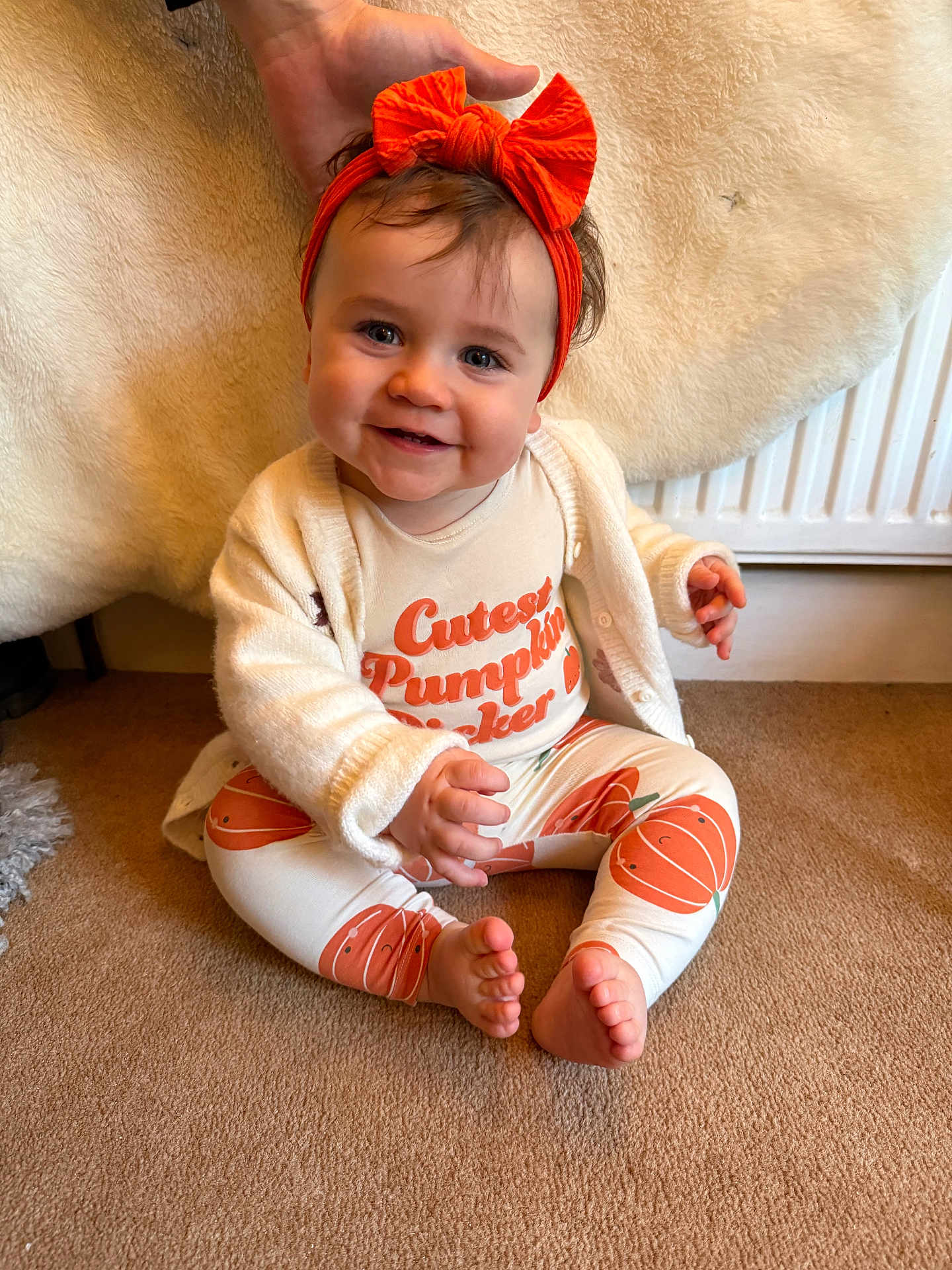 Lily joined the competition — help win amazing prizes! baby, child, smile, headband, orange, pumpkin, carpet, sitting, hand, clothing, cute, indoor, radiator, white_cardigan, feet, portrait, happy, face, infant, cozy
