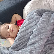 Sarah joined the competition — help win amazing prizes! child, toddler, sleeping, nap, blanket, couch, bottle, red_shirt, gray_blanket, home, indoors, portrait, face, curly_hair, resting, cozy, baby, furniture, soft_texture, peaceful