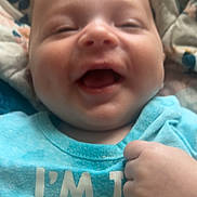 Zaiden is registered to the contest to win money with this photo: baby, smiling, blue_shirt, hand, face, infant, happy, clothing, blanket, closeup, young_child, portrait, cute, skin, mouth_open, lying_down, cheeks, indoors, expression, fingers