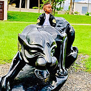 Nathan a rejoint le concours — aidez-le/la à gagner de superbes lots ! child, boy, sculpture, panther, black, jacket, outdoor, grass, greenery, statue, park, young, curious, portrait, casual_clothing, nature, daylight, person, looking_away, concrete