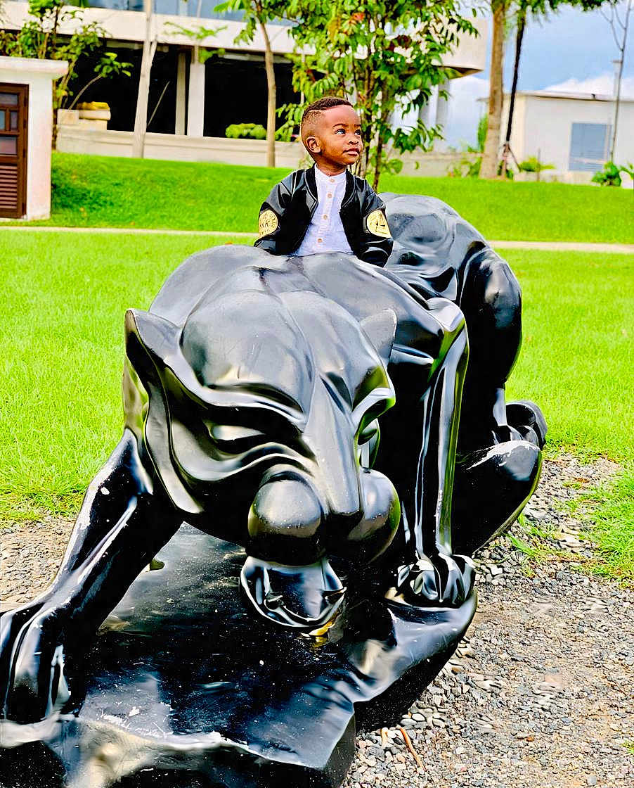 Nathan a rejoint le concours — aidez-le/la à gagner de superbes lots ! child, boy, sculpture, panther, black, jacket, outdoor, grass, greenery, statue, park, young, curious, portrait, casual_clothing, nature, daylight, person, looking_away, concrete