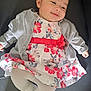 baby, infant, smiling, dress, cardigan, floral_pattern, tights, socks, laying_down, happy, child, cute, portrait, indoor, soft_lighting, cozy, clothing, person, young, face
