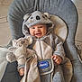 baby, child, smile, koala_costume, plush_toy, blanket, baby_chair, indoor, happy, cute, onesie, infant, cozy, person, soft_toy, seat, comfort, young_child, face, holding