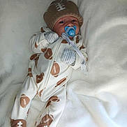 Kingston is registered to the contest to win money with this photo: baby, infant, pacifier, onesie, hat, football_pattern, blanket, sleepwear, cute, lying_down, gloves, footwear, indoors, soft_texture, newborn, child, portrait, cozy, comfort, sleeping_area