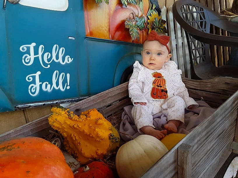 Estella-mae is registered to the contest to win money with this photo: baby, calabaza, chair, cucurbita, event, gourd, grass, happy, headwear, leisure, local_food, natural_foods, orange, people, person, plant, pumpkin, squash, toddler, vegetable