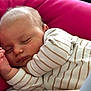 baby, sleeping, infant, cushion, pink, striped_clothing, onesie, hand, face, peaceful, closed_eyes, soft_lighting, skin, cute, resting, child, portrait, indoor, cozy, newborn