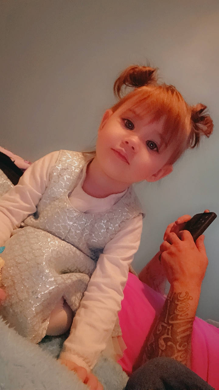 Ameila is registered to the contest to win money with this photo: baby, bodypart, clothing, couch, dress, electronics, eveningdress, face, finger, formalwear, furniture, hand, head, mobilephone, person, phone, photography, sitting, texting, wrist