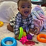 baby, bed, blanket, child, colorful, crib, cute, face, happy, indoor, infant, pajamas, pastel, person, plaid_clothing, playtime, room, smiling, soft, toys