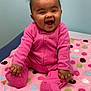 baby, blanket, child, chubby_cheeks, colorful, curly_hair, cute, face, happy, indoor, infant, joyful, onesie, pink_clothing, playful, polka_dot, portrait, sitting, smiling, soft_texture