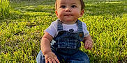 Axel is registered to the contest to win money with this photo: baby, barefoot, casual_clothing, child, curious, cute, daylight, denim_overalls, forest, grass, greenery, nature, outdoor, portrait, sitting, smile, summer, sunlight, trees, young_child